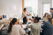 © Maskot - Female entrepreneur discussing business plans with colleagues sitting at table in office meeting room