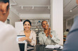 © Maskot - Happy female entrepreneurs sitting at table during business meeting in office