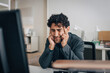 © Maskot - Stressed male entrepreneur touching temples while sitting at desk in creative office