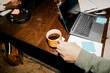 © Maskot - High angle view of male entrepreneur holding coffee cup near laptop on desk at office