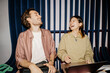 © Maskot - Happy male and female business colleagues laughing while sitting with laptops at office