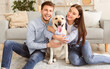© Prostock-studio - Togetherness Concept. Excited friends playing with their pet in the living room, looking at camera