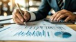 © Hungarian - A person in a suit reviews financial charts and data