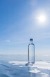 © Katvic - Glass bottle with cold natural drinking water stands on ice of frozen Baikal Lake on cold sunny winter day. Advertising and branding of drinking fresh ecological water. Nature background. Copy space