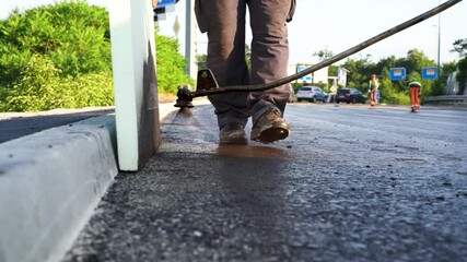 Fototapete - Low angle close-up of process coating fresh asphalt with liquid bitumen next to road curb on highway construction site