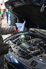 Poster - Serviceman checks the oil level in a car engine