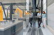 © Westend61 - Man and woman discussing in a production hall with industrial robots
