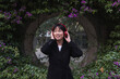 © Westend61 - Young woman in standing in front of flowering bush listening to music with headphones outdoors