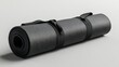 © nanskyblack - A sleek, dark gray yoga mat, rolled and secured with a sturdy black strap, lies poised for the start of a yoga practice or a moment of tranquil meditation, ready to provide comfort and support for a