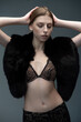 © alipko - Charming young woman in delicate black lace lingerie and luxurious fur wrap, striking a confident pose in a professional studio. Elegant, stylish, and seductive fashion portrait with soft