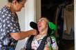 © Austockphoto - Middle aged woman fixing wheelchair strap on son with disability