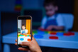 © Vadim - Kid with colorful shapes. A child is engaged in creative play, manipulating colorful shapes while an adult captures the moment on a phone.