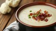 © Thanagorn - Creamy soup topped with crispy bacon and green onions, served in a rustic bowl on a wooden surface, garnished for an inviting presentation.