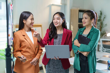 Wall Mural - asian businesswomen collaborating, planning strategy in contemporary workspace, analyzing data on la