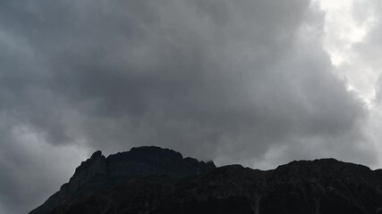 Wall Mural - Time lapse of grey storm clouds blowing across the top of a rocky mountain ridge
