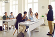 © Studio Romantic - Smart girl student presenting project homework during lecture at college. Teacher listens to girl's answer as she speaks while standing in classroom surrounded by her classmates. Learning concept.
