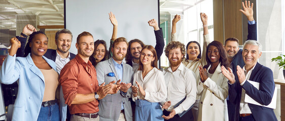 portrait of diverse happy business people standing in office applauding and looking cheerful at the 