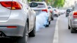 Cars are stuck in heavy traffic on an urban street during the afternoon. Exhaust fumes are visible, contributing to air pollution and smog in the city