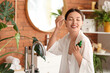 © Pixel-Shot - Beautiful Asian woman applying serum in bathroom
