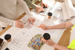 © Pixel-Shot - Team of constructors with coffee and house plan working at table in office, closeup