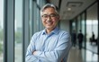 © Nina - Confident Middle-Aged Asian Man in Light Blue Shirt Standing in Modern Corporate Environment with Large Windows Overlooking Cityscape