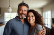 © Vorda Berge - Portrait of a smiling middle aged Hispanic couple in new home with moving boxes