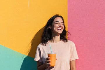 Wall Mural - portrait of laughing woman holding smoothie standing in front of colorful urban mural sunny day copy