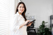 © NAMPIX - Portrait of happy businesswoman with touchpad in office looking outside.
