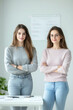 © Platoo studio - Two confident women standing with arms crossed in modern office, smiling and looking at camera