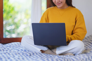 Wall Mural - closeup of a woman using and working on laptop computer while sitting on bed