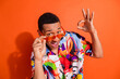 © deagreez - Charming man with vibrant fashion sense showcases confident pose against bright orange backdrop, exuding positivity and modern lifestyle.