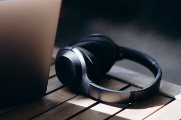 Wireless headphones lying on table by the laptop in a cafe