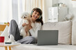 © LIGHTFIELD STUDIOS - Young woman enjoys cozy afternoon with her dog while video chatting at home