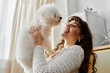 © LIGHTFIELD STUDIOS - Joyful moments shared between a young woman and her fluffy companion in a sunny room