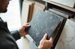 © Vadym - Man selecting stone kitchen countertop panel at furniture store. Person holds grey marble sample. Home improvement, design choice for interior construction, renovation. Modern house decor catalog