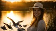 © wen - Portrait of a beautiful, smiling woman wearing a hat, standing by a lake with birds at sunset,