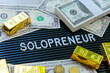 © ponsulak - Business concept. Gold bars and dollars on a black background with the word solopreneur.