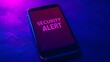 © Tanakrit - A smartphone displaying a glowing 'SECURITY ALERT' message, set against a dark background with purple lighting.