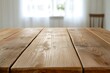© Sengphachanh25 - Light brown wooden table against a bright, blurred background of a white room with a window. The focus is sharply on the wooden surface.