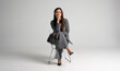 © opolja - Portrait of a cheerful young businesswoman sitting in a chair against white background.