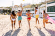 © Xavier Lorenzo - Rear view of group of friends running on the beach having fun on summer vacation, beach houses on background