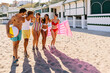 © Xavier Lorenzo - Happy multi-ethnic friends walking along the beach, soaking up the sun and enjoying their carefree summer vacation together