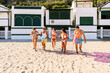 © Xavier Lorenzo - Front view of group of friends joyfully running along the beach, enjoying their summer holidays filled with laughter, energy, and carefree moments together. Friendship lifestyle concept