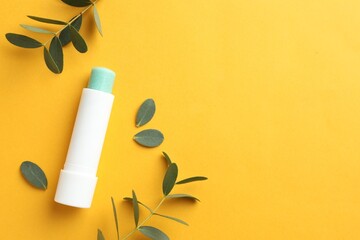Wall Mural - lip balm and eucalyptus leaves on yellow background, flat lay. space for text