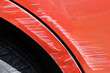 © esvetleishaya - Close up of a red car with multiple visible scratches and paint damage The scratches expose the underlying metal, creating a contrast against the glossy surface. Perfect for automotive damage concepts
