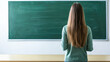 © romanets_v - Caucasian female teacher standing alone in classroom facing green chalkboard with long hair