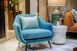 © malayeka - Teal blue velvet armchair with a light gray pillow in a modern living room, featuring a round white side table, a lamp, and a beige sofa.