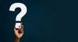 © Dmitry - African american man holding big question mark cutout against dark blue background, seeking answers, copy space. Posing questions and searching for solutions.