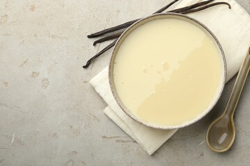 Wall Mural - Tasty condensed milk, spoon and vanilla pods on light grey table, flat lay. Space for text