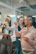© Zamrznuti tonovi - Businesswomen planning strategy using sticky notes on glass wall in office